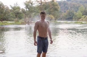 man with a bare torso splashing water photo