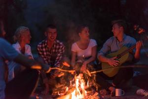 young friends relaxing around campfire photo