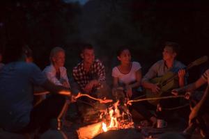 young friends relaxing around campfire photo