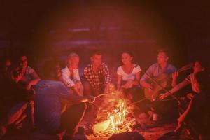 young friends relaxing around campfire photo