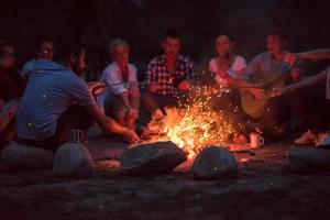 young friends relaxing around campfire photo