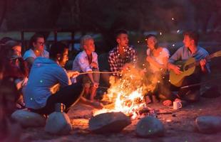 jóvenes amigos relajándose alrededor de una fogata foto