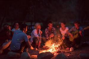 young friends relaxing around campfire photo