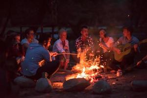 young friends relaxing around campfire photo