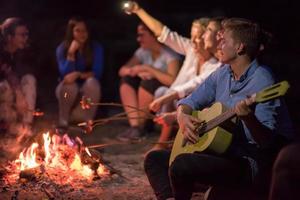 young friends relaxing around campfire photo