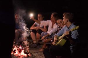 young friends relaxing around campfire photo