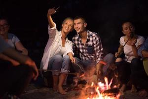 young friends relaxing around campfire photo