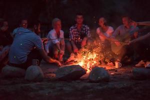 young friends relaxing around campfire photo