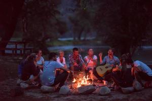 young friends relaxing around campfire photo