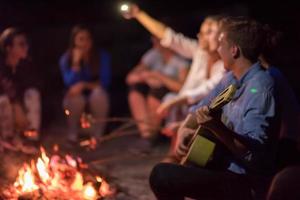 young friends relaxing around campfire photo