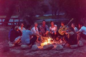 young friends relaxing around campfire photo