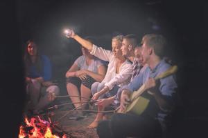 young friends relaxing around campfire photo