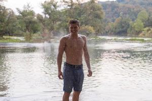 man with a bare torso splashing water photo