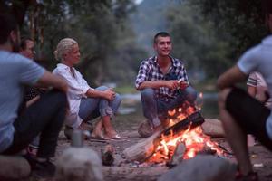 young friends relaxing around campfire photo