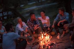 young friends relaxing around campfire photo