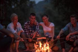 young friends relaxing around campfire photo