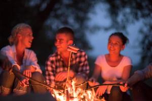 young friends relaxing around campfire photo