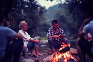 young friends relaxing around campfire photo