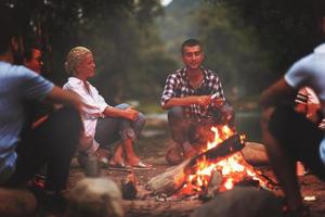 young friends relaxing around campfire photo