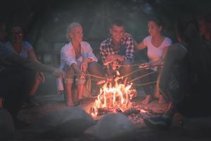 young friends relaxing around campfire photo