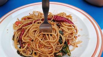 Asian woman using a fork to scoop Spicy spaghetti pork. Drunken Spaghetti Thai call Popular in street food video