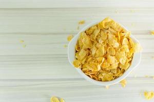 image  Close up Cornflakes cereal breakfast in white bowl on wooden table. photo