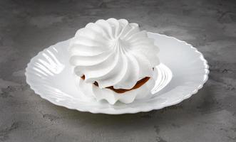 Two snow-white meringues on a white plate. Beautiful white cake. concrete background. photo