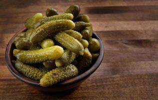 A cup of crispy pickled cucumbers stands on a wooden cutting board. Salted cucumbers. photo