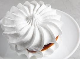 Beautiful white meringues on a white plate. White cake. photo