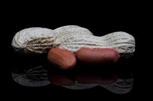 Peanuts in the shell and without it reflect on a black background. photo