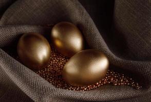 Golden eggs lie on gold sand. photo