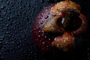 Beautiful ripe mangosteen with water drops on the peel on a dark background.Beautiful ripe mangosteen with water drops on the peel. Water drops in the background. photo