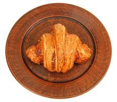 Croissant on a clay plate isolated on white background. View from above . photo