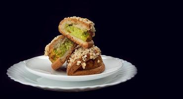 Delicious sliced pastries with pistachio curd and nuts on a white plate. photo