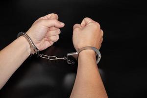 handcuffs arrest, detention of a woman for a crime on dark background photo