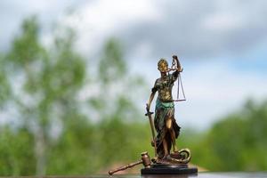 estatua de themis contra un fondo de naturaleza. símbolo de justicia y ley, crimen y castigo. foto