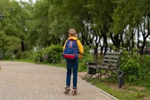boy in a yellow sweatshirt with a backpack on his back going to school. back to school concept photo