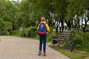 chico con una sudadera amarilla con una mochila en la espalda yendo a la escuela. concepto de regreso a la escuela foto