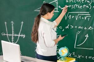 Girl writes mathematical examples on the school board. solves a geometry problem. photo