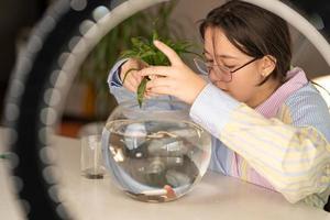 a girl blogger records a video on how to properly change the water in an aquarium and take care of fish photo