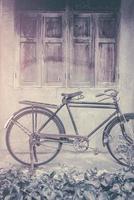 Old rusty vintage bicycle standing near concrete wall photo