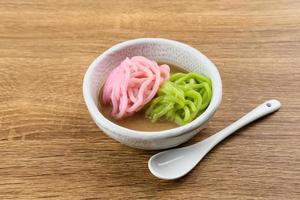 Kue Putu Mayang is traditional Indonesian snack made from rice flour strands curled up into a ball, served with coconut milk and palm sugar. Selected focus. photo