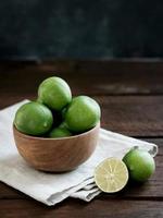 frutas cítricas de lima frescas en un tazón de madera sobre la mesa. foto