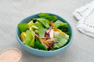 Green salad from green leaves mix vegetables, with mayonnaise sauce. Served in tosca bowl on grey table photo