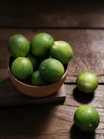 Fresh lime citrus fruits in wooden bowl on the table. photo