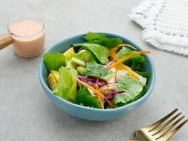 Green salad from green leaves mix vegetables, with mayonnaise sauce. Served in tosca bowl on grey table photo