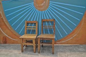 sillas básicas de madera antiguas y fondo de pared de abanico chino azul foto