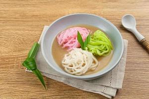 Kue Putu Mayang is traditional Indonesian snack made from rice flour strands curled up into a ball, served with coconut milk and palm sugar. Selected focus. photo