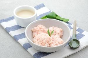 kue putu mayang es un bocadillo tradicional indonesio hecho con hebras de harina de arroz enrolladas en una bola, servida con leche de coco y azúcar de palma. foto
