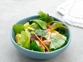 Green salad from green leaves mix vegetables, with mayonnaise sauce. Served in tosca bowl on grey table photo
